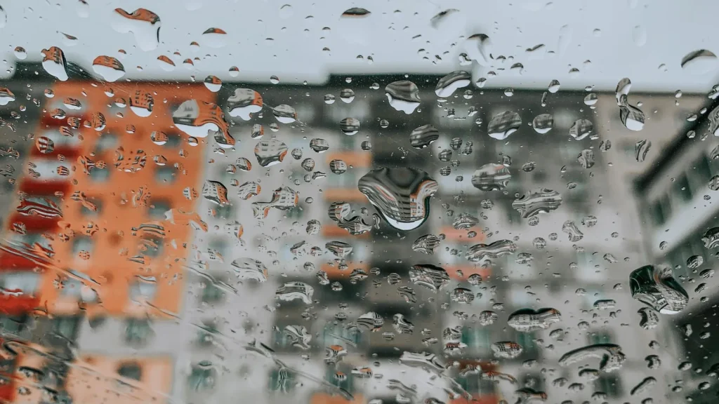 Ventana con gotas de lluvia y edificios al fondo